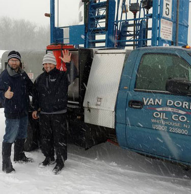 Happy Van Doren Oil Company employees in snow in front of truck, waving